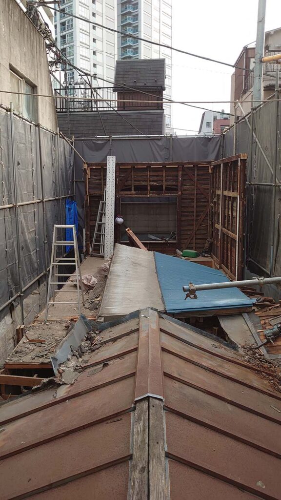 東京都中野区中野の商店街で、重機を使わず手壊しによる木造店舗解体を行っている様子