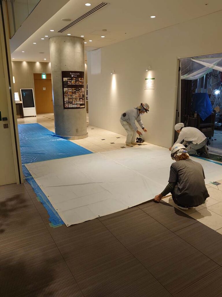 館内通路を約50m養生し、箱台車も防塵対策を行ったうえで廃材を搬出している様子（新宿区）